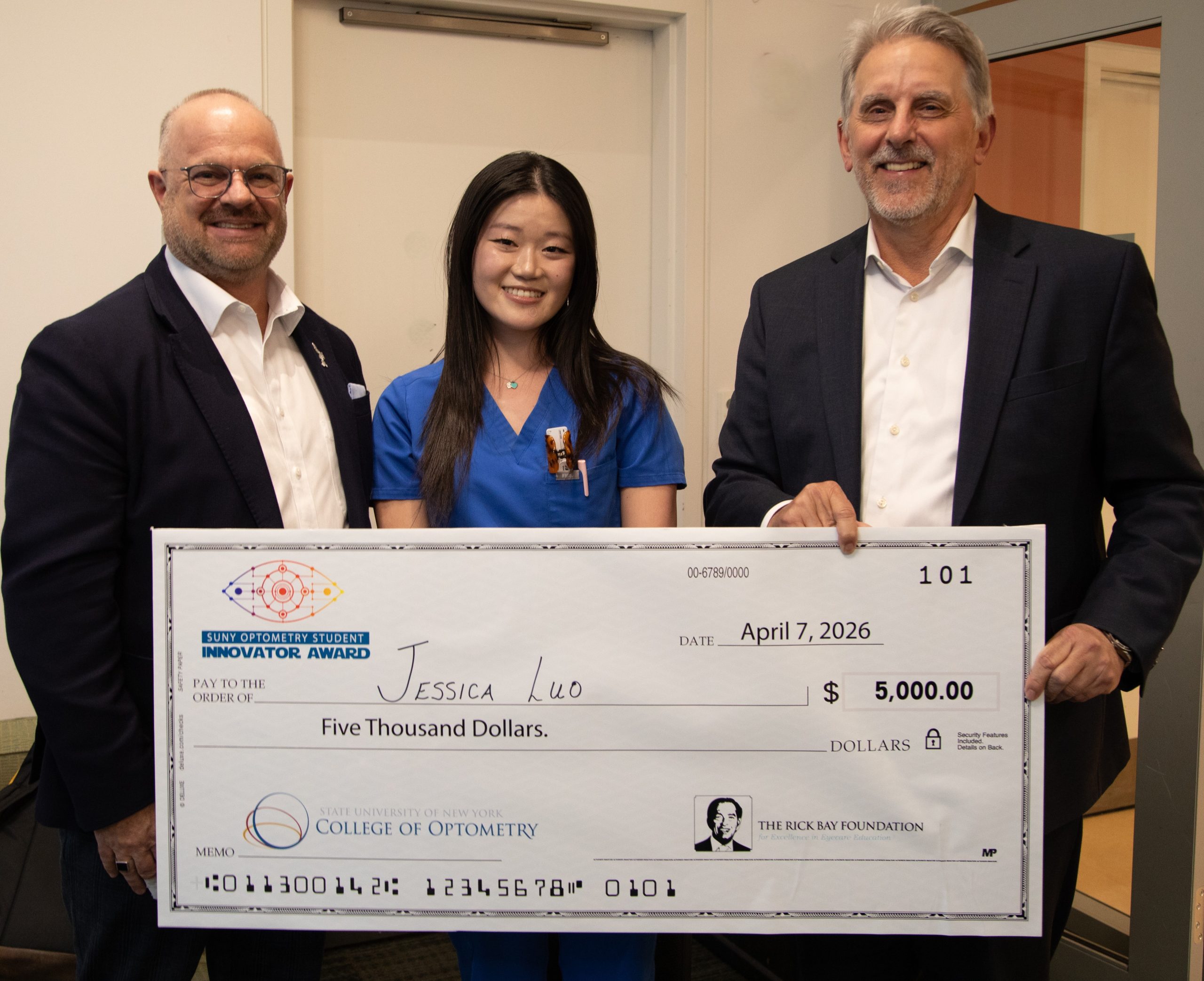 Three people, including student award winner, holding oversized check.
